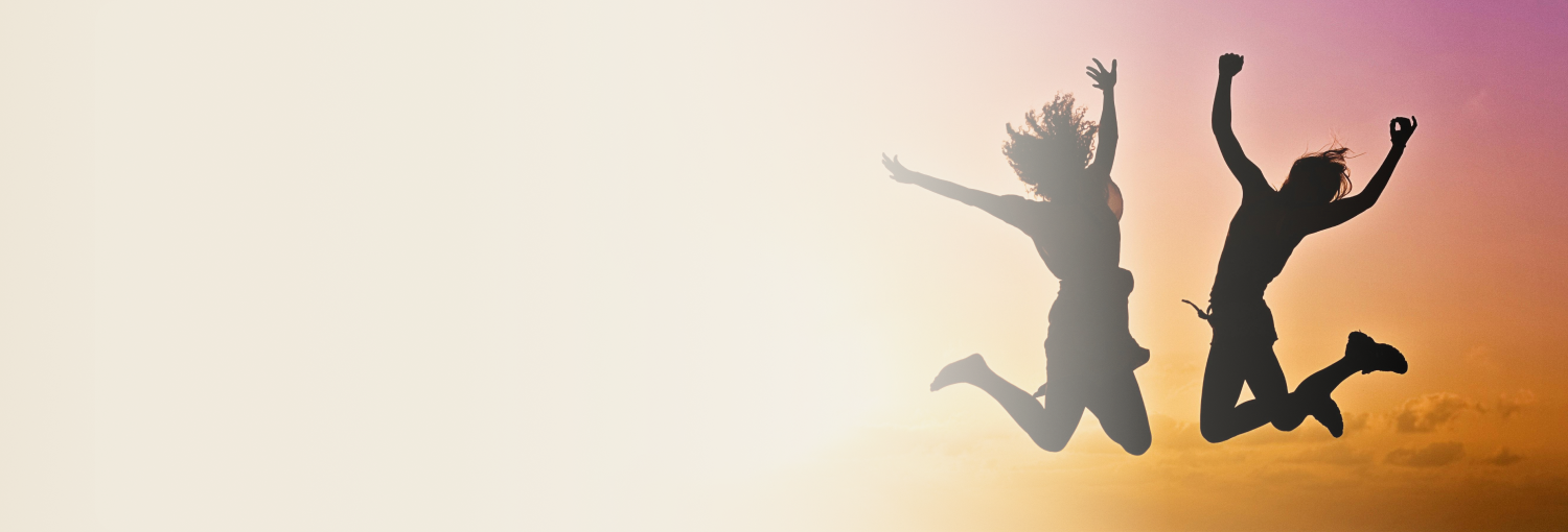 Experience the joy of movement Two teenagers silhouetted jumping with raised arms against an orange and purple sunset, expressing joy and freedom.