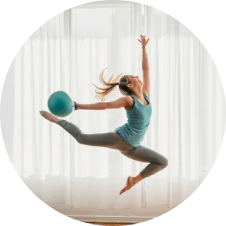 Physical well being Woman leaping with a blue exercise ball overhead, showcasing a dynamic, confident pose.