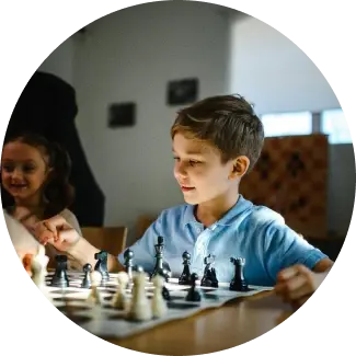 Better decisions Young boy in blue shirt playing chess, focused on developing strategic thinking skills.