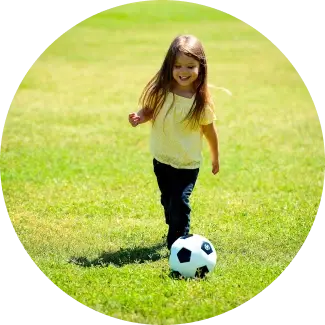 Improved self confidence Girl in yellow top playing soccer on a grassy field, enjoying active play.