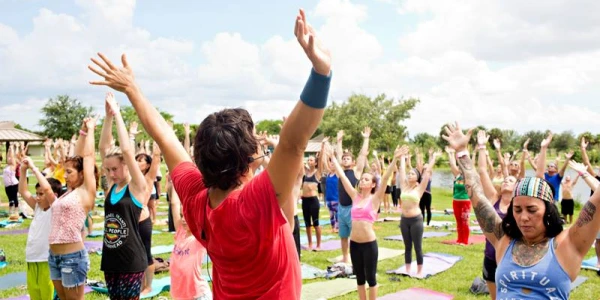 Join AOL Volunteer Community Enthusiastic group of Art of Living volunteers raising hands in unity during outdoor community service event
